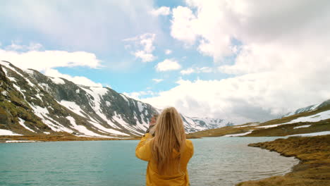 woman taking picture of a mountain lake scene