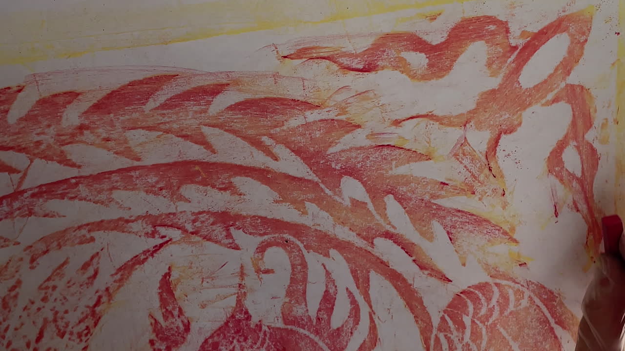 Primo piano di una mano che traccia il design sottostante usando carboncino rosso su carta artistica