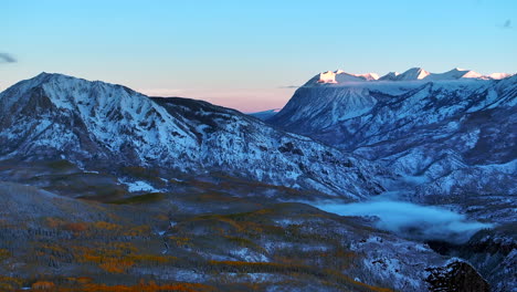 first light kebler pass crested butte gunnison colorado seasons crash aerial drone early fall aspen tree red yellow orange forest winter first snow cold sunrise clouds rocky mountain peak back motion