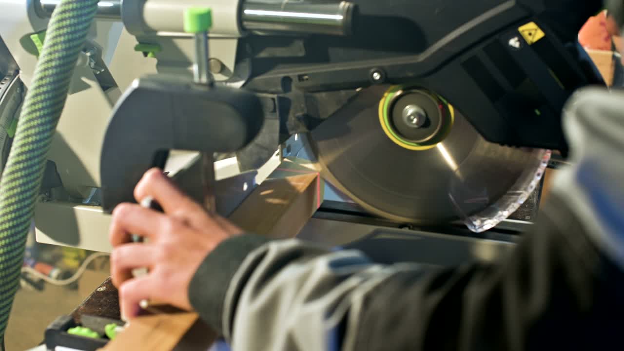 primer plano de la mano de un hombre trabajando en una máquina con una sierra circular