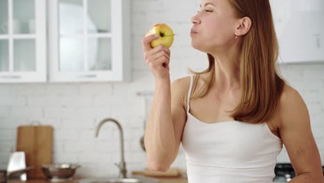 young woman with brown hair eating apple. portrait concept. healthy lifestyle. girl in a white t-shirt in the kitchen