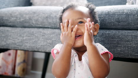cute baby girl playing peek a boo at home
