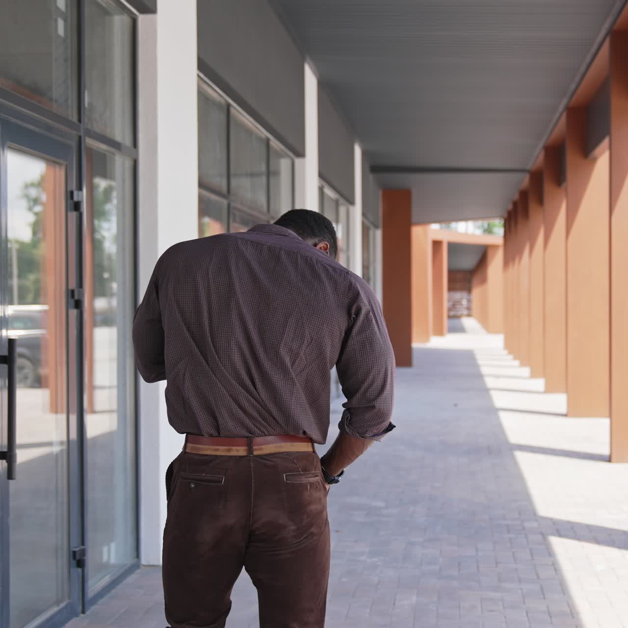 African american man talking the phone outdoors. Back view of unrecognizable man solving business problems through the phone in the city. Rear view