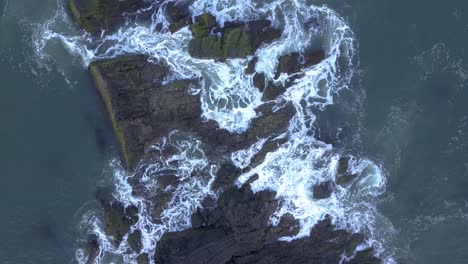 Waves-Crashing-On-Rocks---Sea-Waves-With-White-Foam-Breaking-On-Coast-In-Galgibaga-Beach,-South-Goa,-India---aerial,-top-down