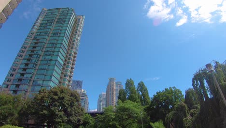 low angle view of tall skyscrapers and tree tops near city center of vancouver bc canada