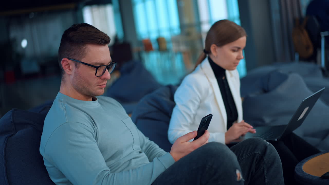 Coworkers Working on Laptops and Phones in a Modern Office