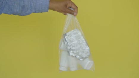 a person's hand holding a plastic bag filled with pills and medication