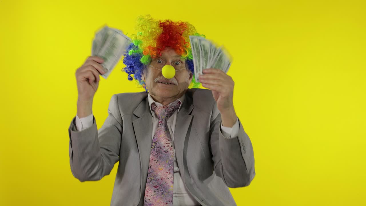 Anziano uomo d'affari clown freelance che balla con banconote in dollari.
