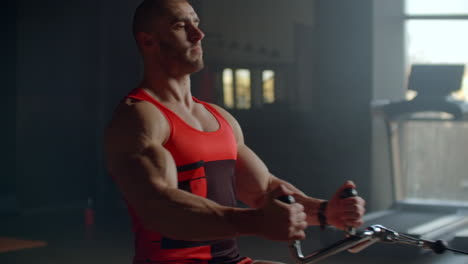 young man doing workouts on a back with power exercise machine in a gym club. at athletic man doing workouts on a back with power exercise machine in a gym on the background of large windows.