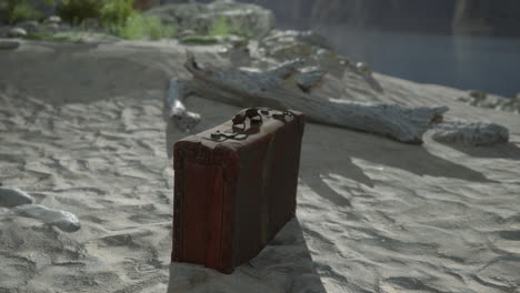una maleta antigua abandonada en una playa de arena.