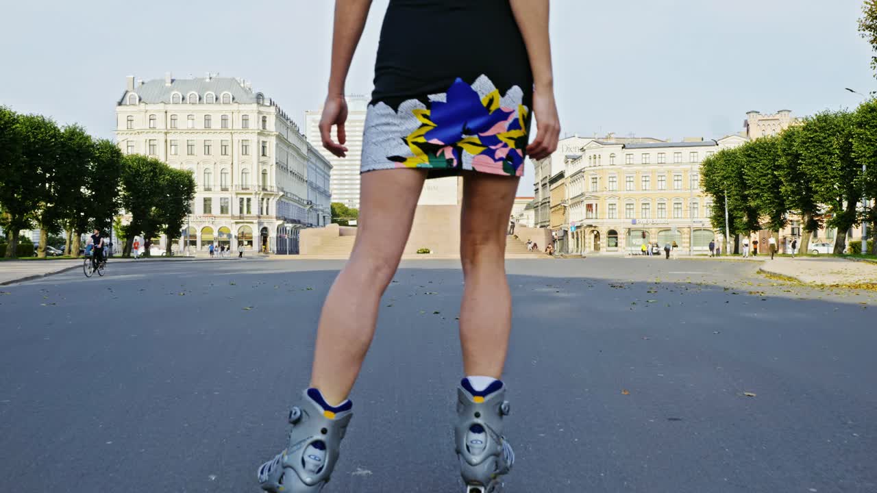 Donna bionda sui pattini in linea vicino al Monumento alla Libertà di Riga, ripresa in slow motion con luce serale.