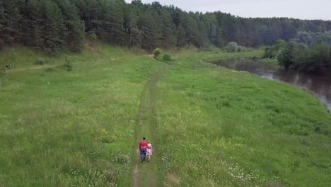 una pareja caminando por un prado junto a un río en un bosque