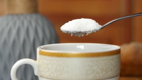 movimiento lento de verter azúcar blanco en una taza de té