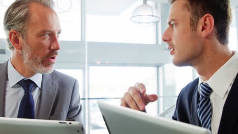 two men, with their tablets, speaking together