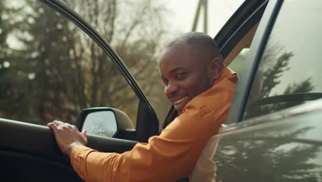 handsome african male driver getting out from car