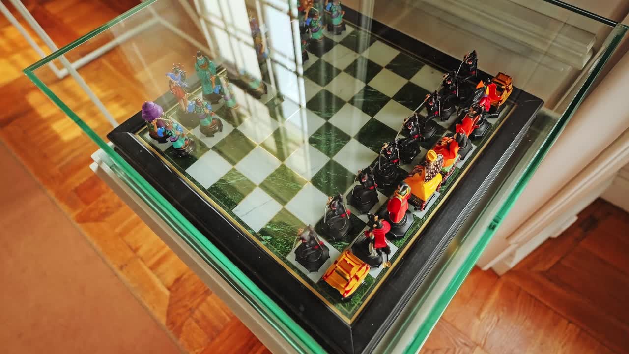 Vintage chess set display with colorful figures and reflection on museum glass