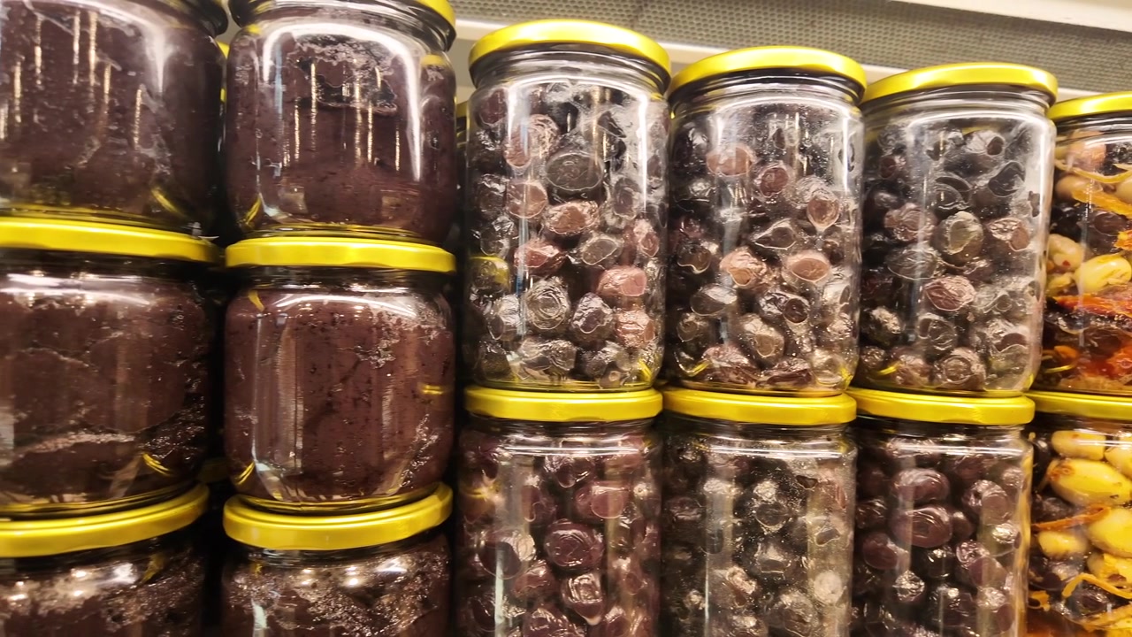 Rows of Glass Jars Filled with Olives and Olive Paste on Supermarket Shelves