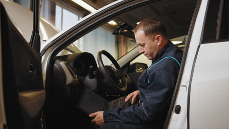 mechanic working on a car with a laptop