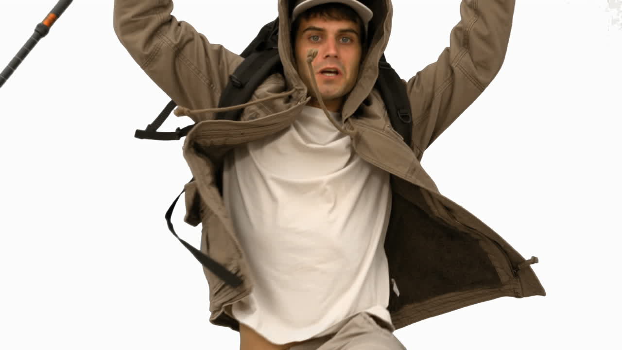 hombre con un bastón de senderismo saltando en la pantalla blanca