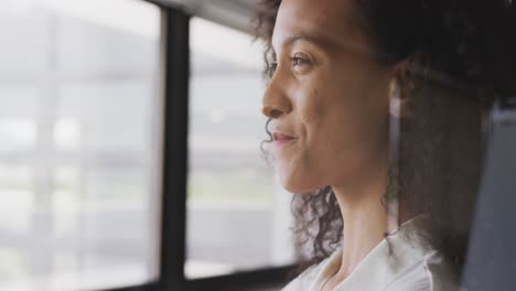 professional businesswoman smiling while looking out of a window from her office in slow motion