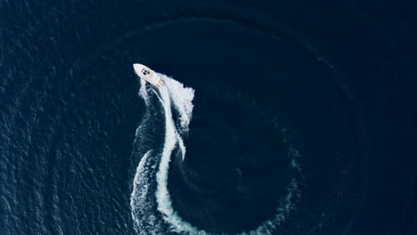 aerial top down view of speed boat circling around on iseo lake, italy