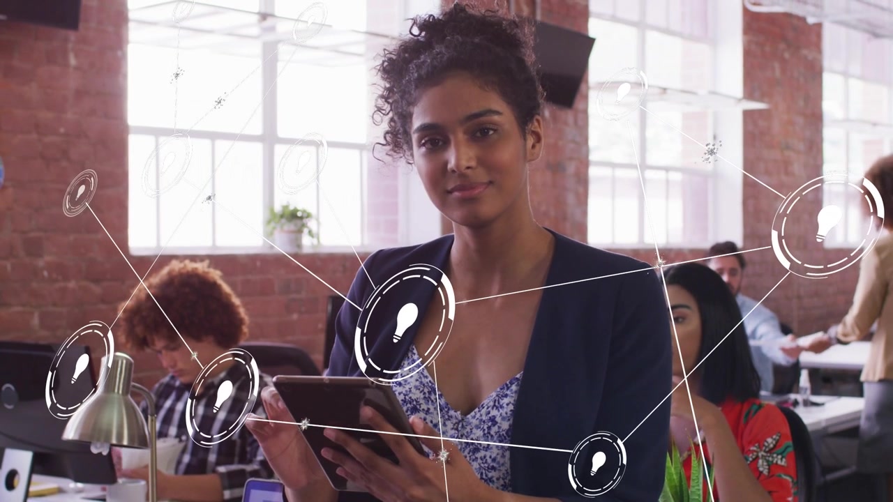 Woman standing center tapping tablet in office and activating network nodes, mapping business links
