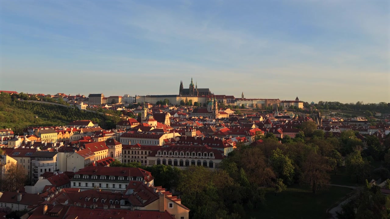 Vista aerea con drone dei tetti di tegole rosse di Malá Strana e del Castello di Praga con la Cattedrale di San Vito che corona la collina sotto un cielo primaverile limpido e azzurro
