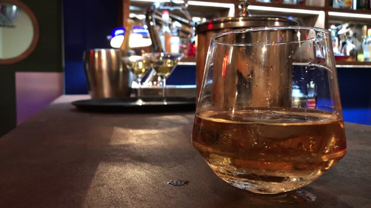 Caduta di un cubetto di ghiaccio in un bicchiere di whisky freddo - Primo piano