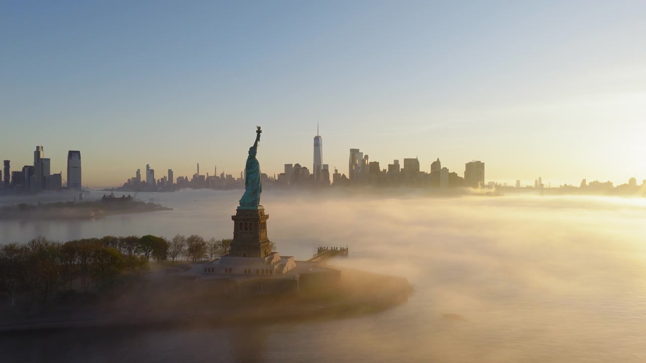 Video udara menakjubkan menangkap Patung Liberty saat matahari terbit, dikelilingi kabut pagi dengan cakrawala New York bersinar dalam cahaya jam emas