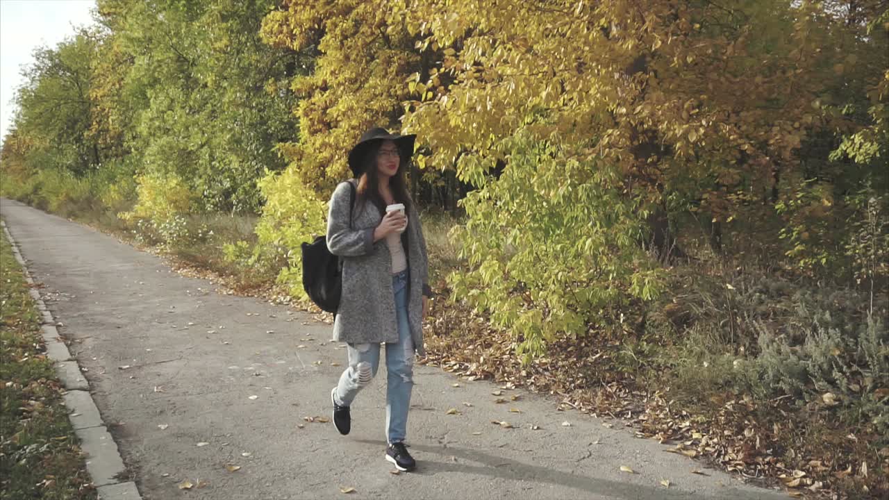 mujer caminando en el parque de otoño con café