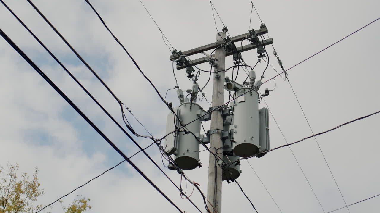 A power line pole with transformers on it. Typical of the United States