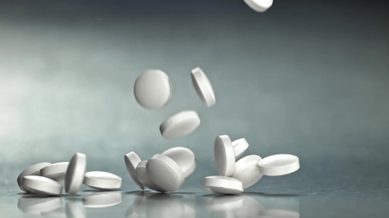 Pastillas de medicamento blancas cayendo a cámara lenta