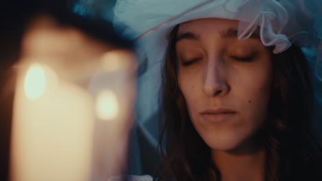 contemplative woman in veil by candlelight