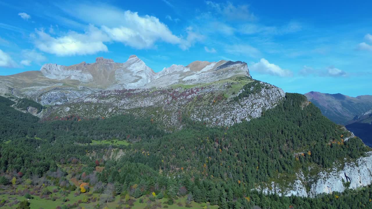 Lush forest and rocky mountains under a bright blue sky near canfranc in aragón, spain, aerial view