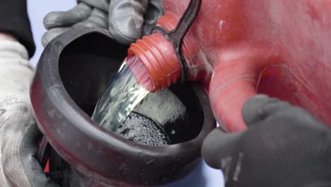 vertiendo gas combustible en el tanque del coche de carreras desde la olla de combustible por dos mecánicos en cámara lenta