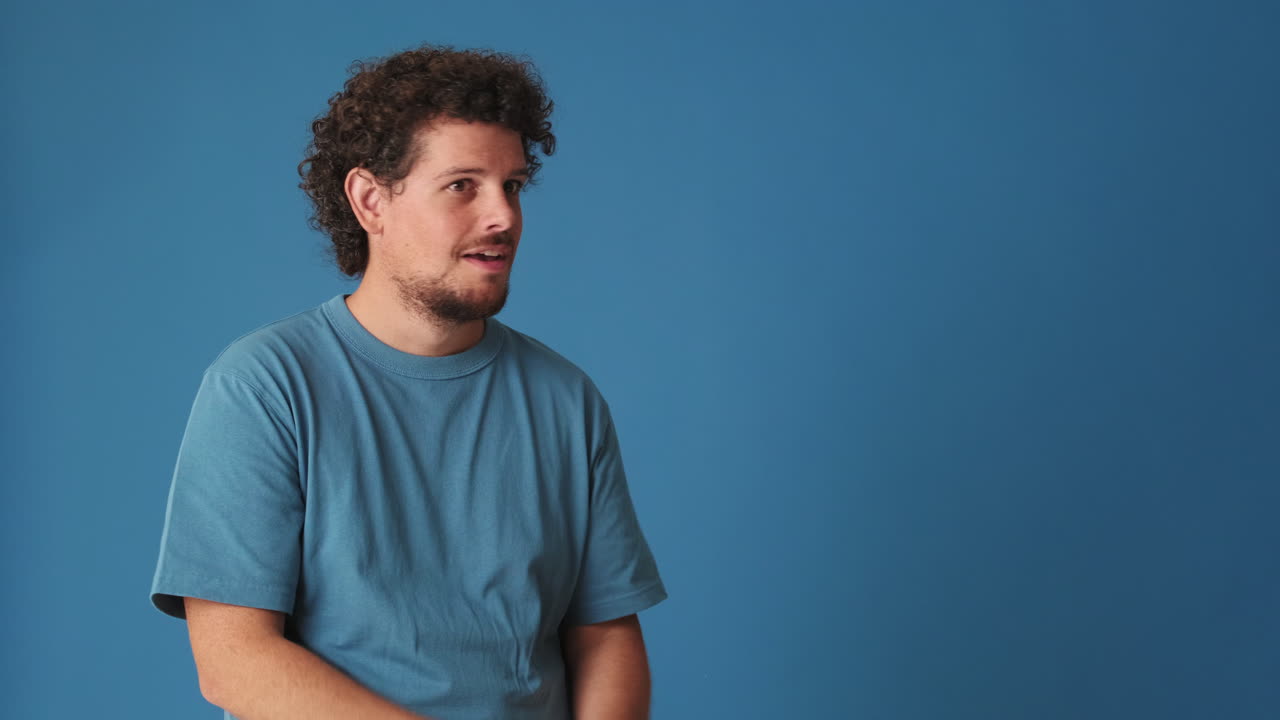 Happy Man Smiling and Pointing to Copy Space on Blue Background