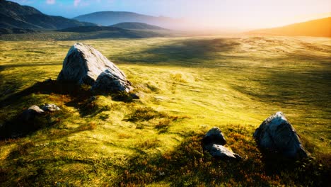 meadow with huge stones among the grass on the hillside at sunset