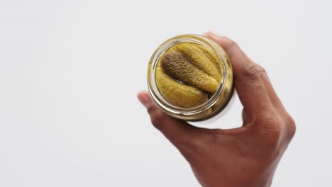 a hand holding a jar of pickles