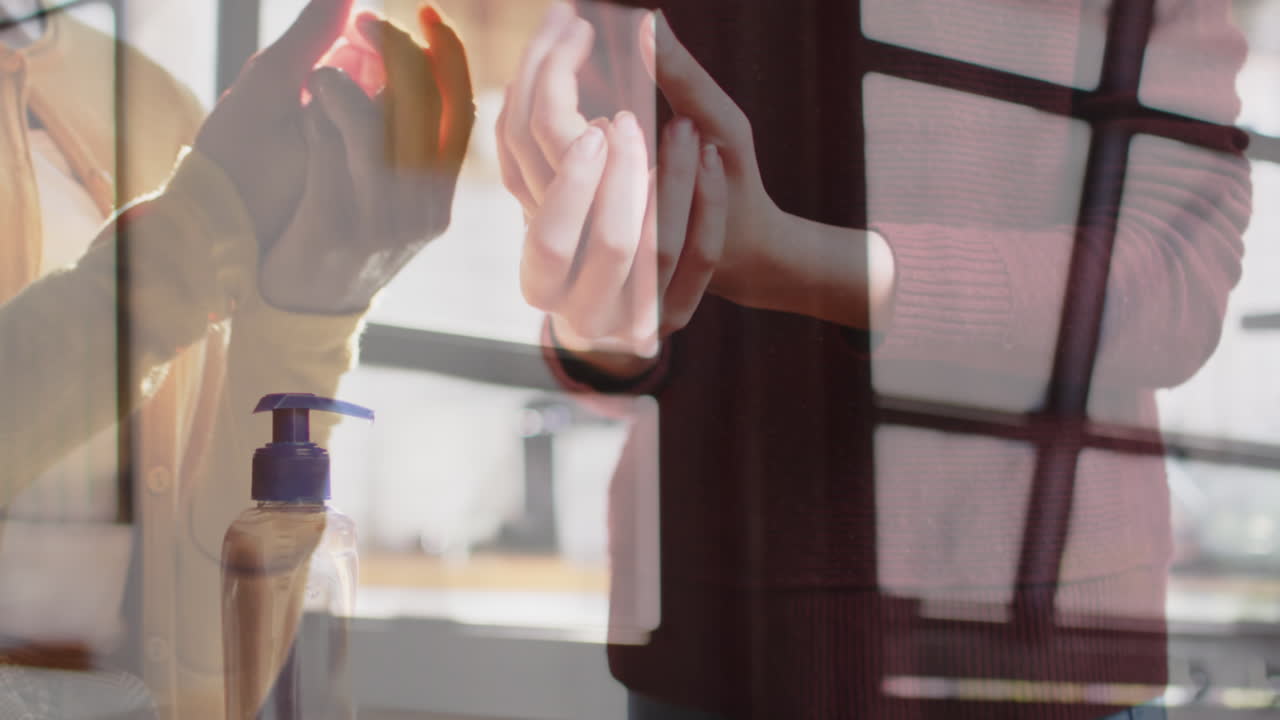 様々な同僚が作業中に手を消毒している光と窓のビデオ