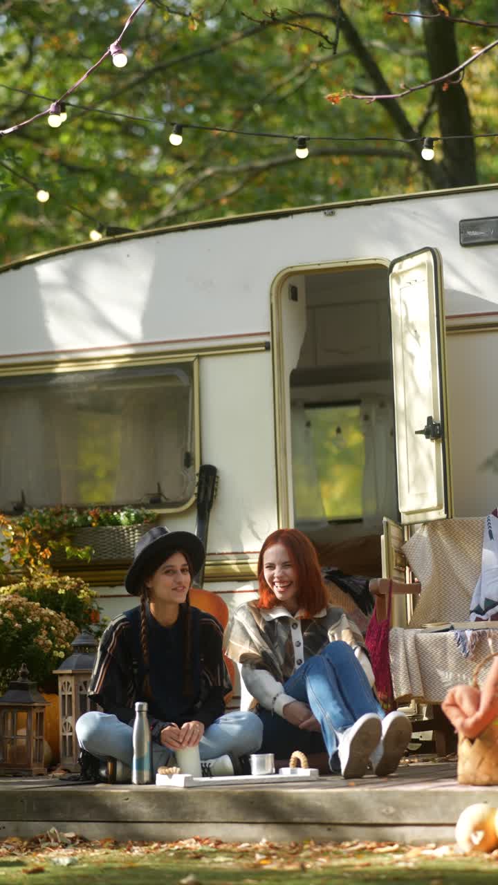 두 명의 여성이 캠퍼 밴에 의해 가을 피크닉을 즐기고 있습니다.
