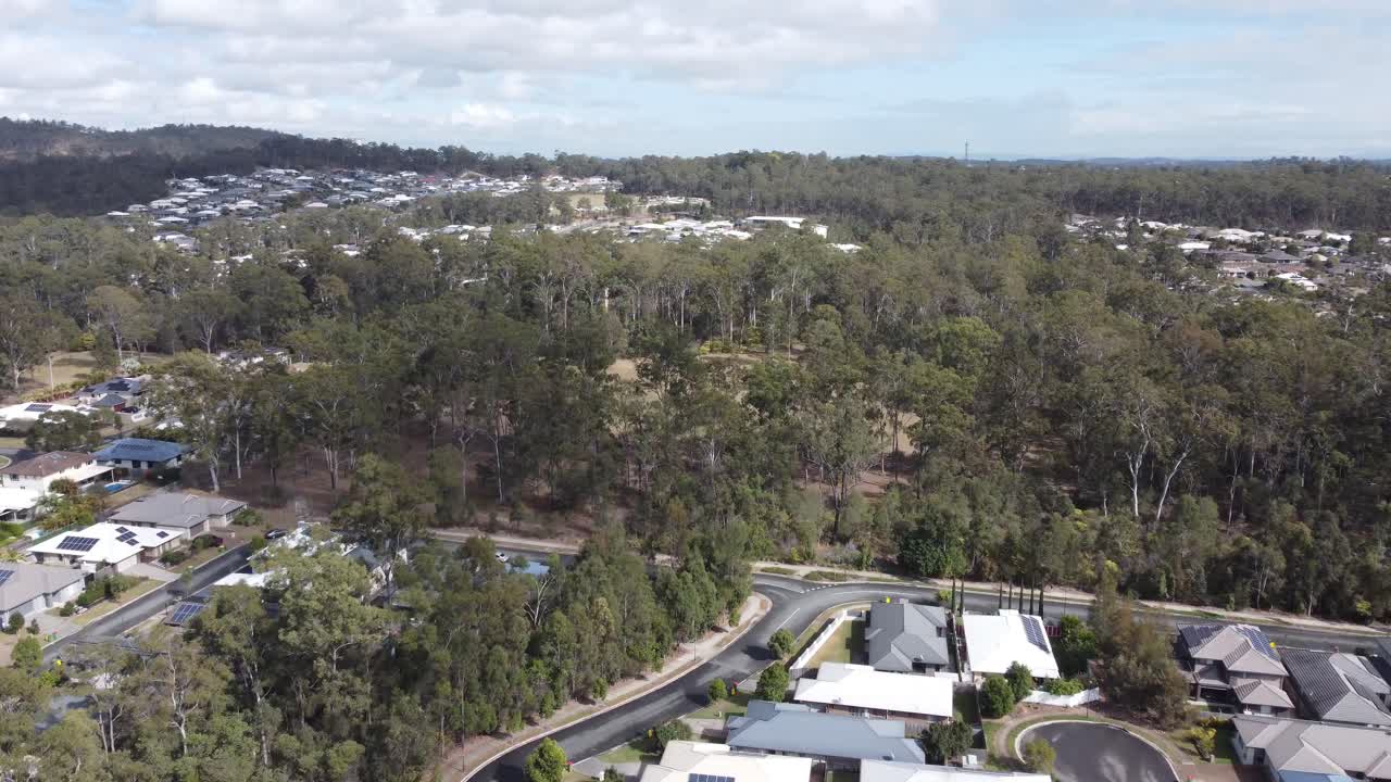 vista aérea de un complejo residencial en australia, avión no tripulado volando sobre las casas hacia el bosque y un campo verde