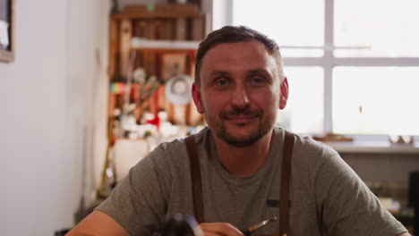 Positive-man-with-smoking-pipe-and-apron-in-small-workshop