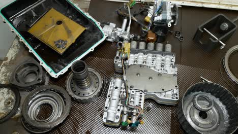 a top down view of a mechanics workbench showcasing parts of a transmission torn apart on it