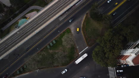 drone over an intersection in buenos aires, cars drive along the roads, next to the railway