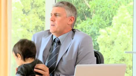 hombre de negocios trabajando en el escritorio con el bebé