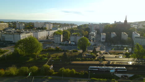 tren que viaja por el ferrocarril con vistas a la torre de la iglesia parroquial de san antonio y la hermosa ciudad de gdynia, voivodato de pomerania, polonia