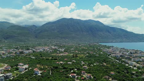 aerial establishing shot, wide view of kalamata seaside, taygetos mountain on background and olive grove in foreground, push out, right pan movement 4k