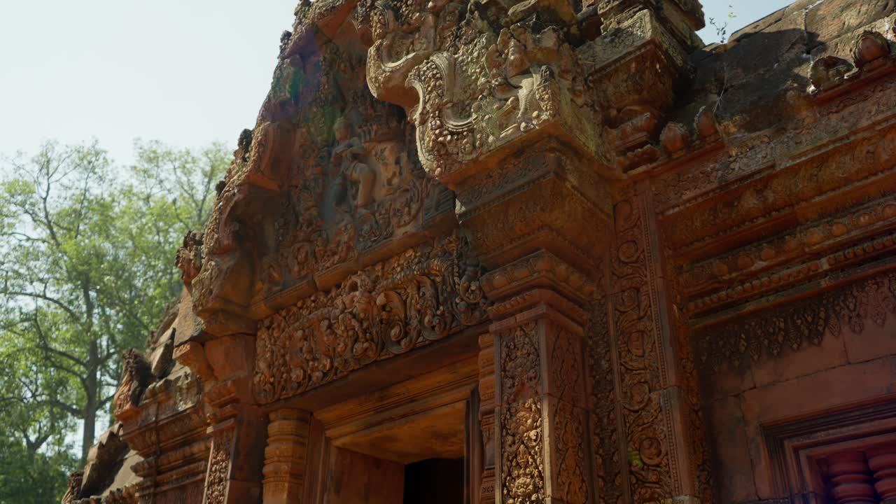 Ornate stone carvings on Banteay Srei Temple, glowing in warm sunlight, Cambodia