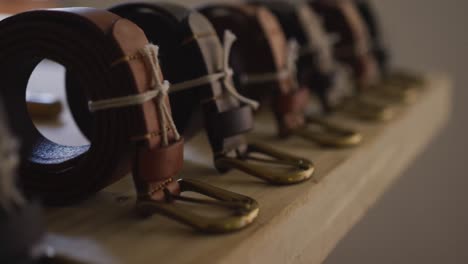 close up of ready to wear leather belts lined in leather workshop