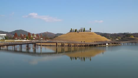 korean tourists walking along bridge of dreams in suncheonman bay lake garden on sunny autumn day, suncheon city, south korea